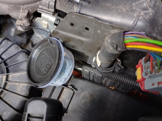 A rat bait block inside a small plastic container with an access hole. Attached by a cable tie inside the engine bay.