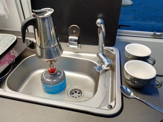 A stovetop coffee maker on a camp cooker.